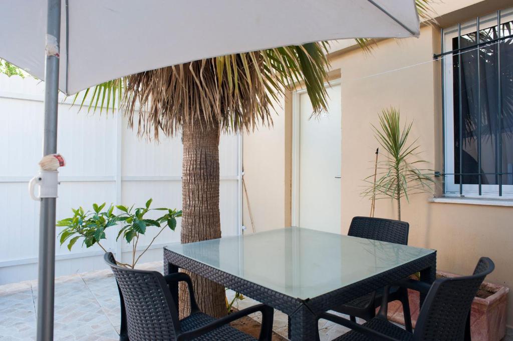 een glazen tafel met stoelen en een palmboom bij Geula Suites BY RAPHAEL HOTELS in Tel Aviv