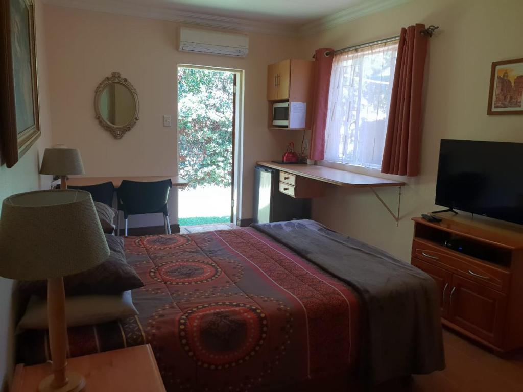 a bedroom with a bed and a television and a window at Accommodation@Bourne in Centurion