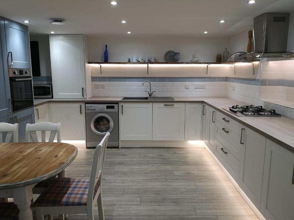 a kitchen with white cabinets and a table and a sink at GAINESVILLE in South Shields