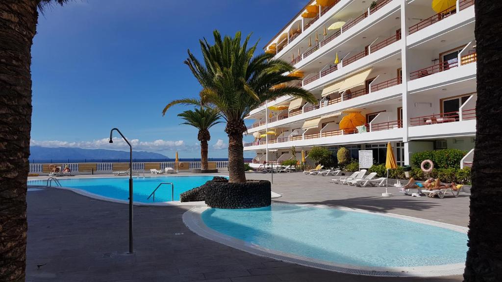 un gran hotel con piscina y palmeras en Playa de la Arena Apartment, en Puerto de Santiago