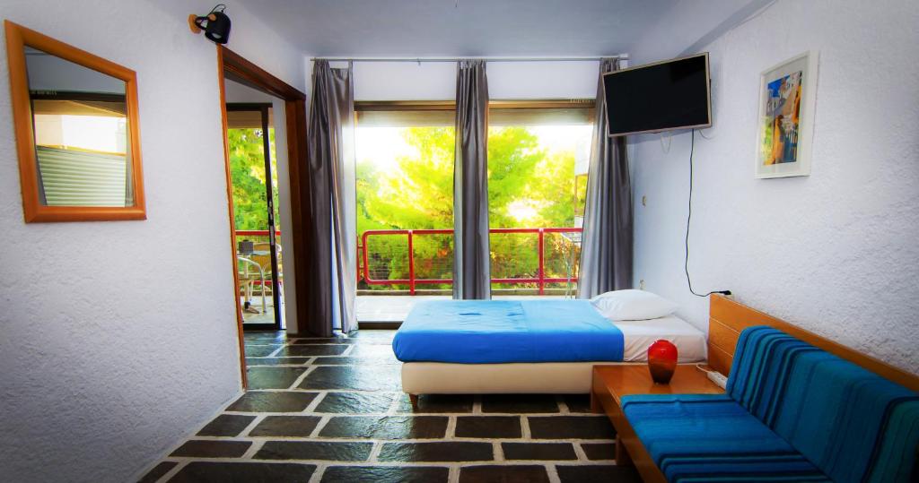 a bedroom with a bed and a couch and a window at Apollonia Hotel Apartments in Varkiza
