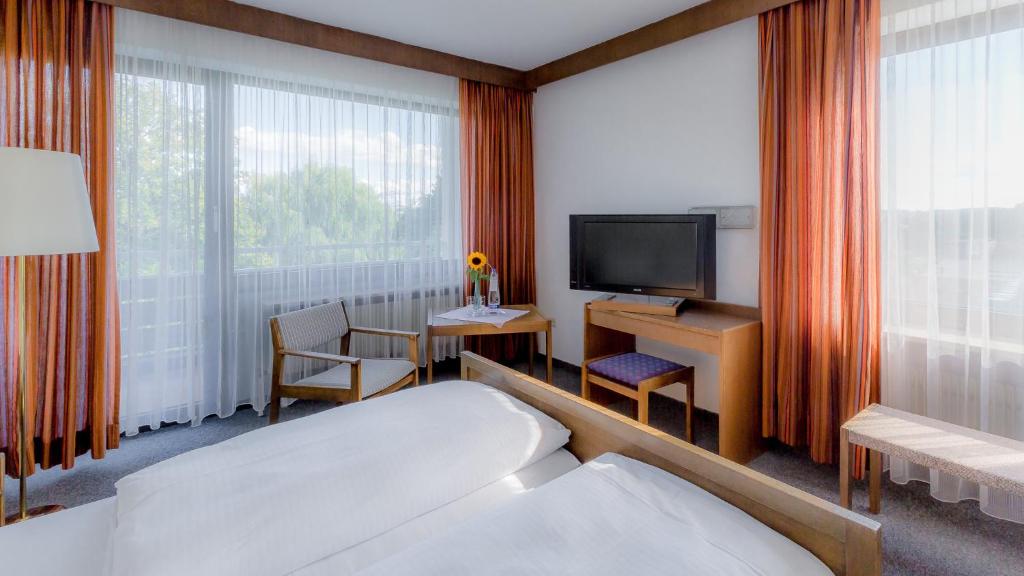 a hotel room with a bed and a television at Hotel Parsberg in Puchheim