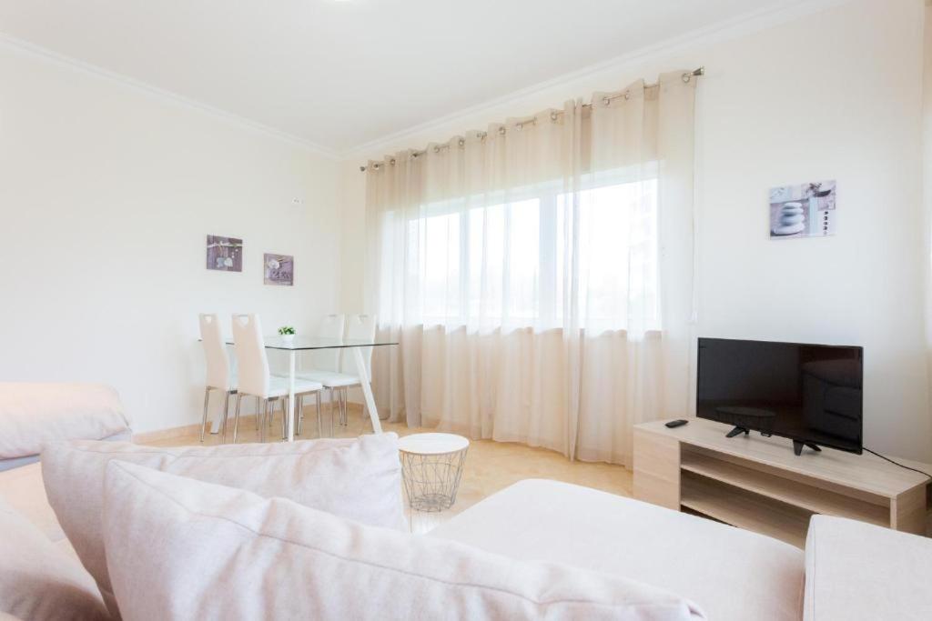 uma sala de estar branca com um sofá e uma televisão em ELEGANZ HOUSE em Portimão