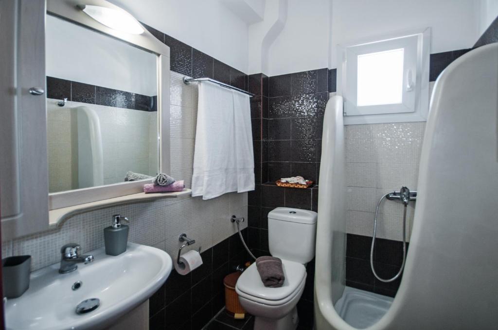 łazienka z umywalką, toaletą i lustrem w obiekcie Veldi Art - Kamari Beach Apartment w Firze