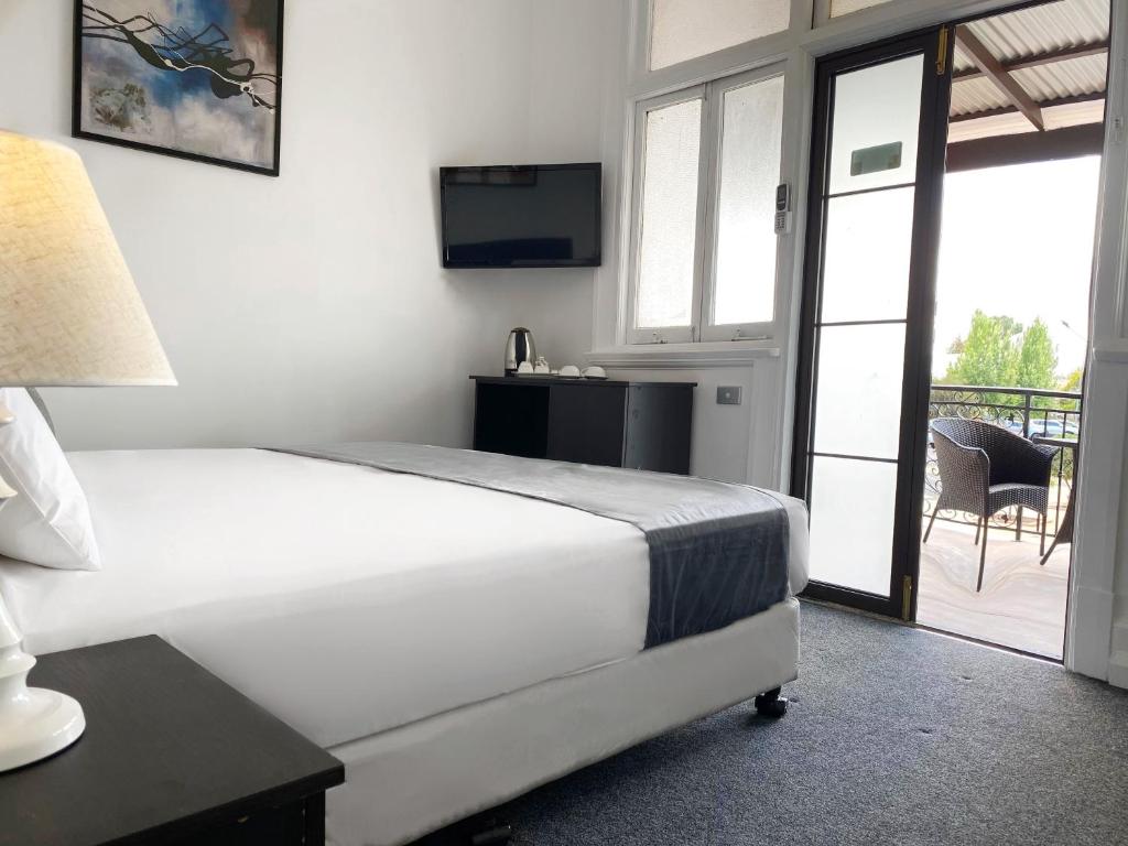 een slaapkamer met een bed, een televisie en een balkon bij Commercial Motel in Hay