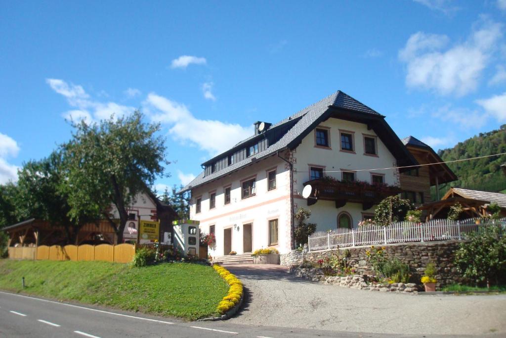 une grande maison blanche sur le côté d'une route dans l'établissement Gästehaus Moser, à Ramingstein