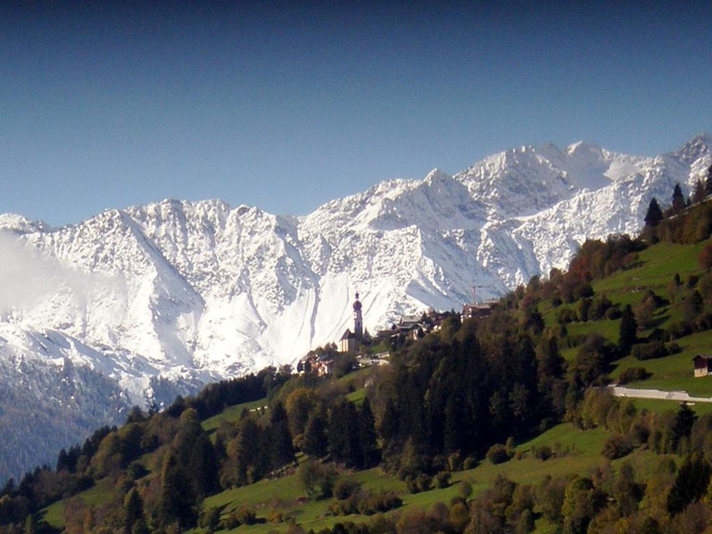 a snow covered mountain range with a town on a hill at Alp-Hof Apartments in Racines