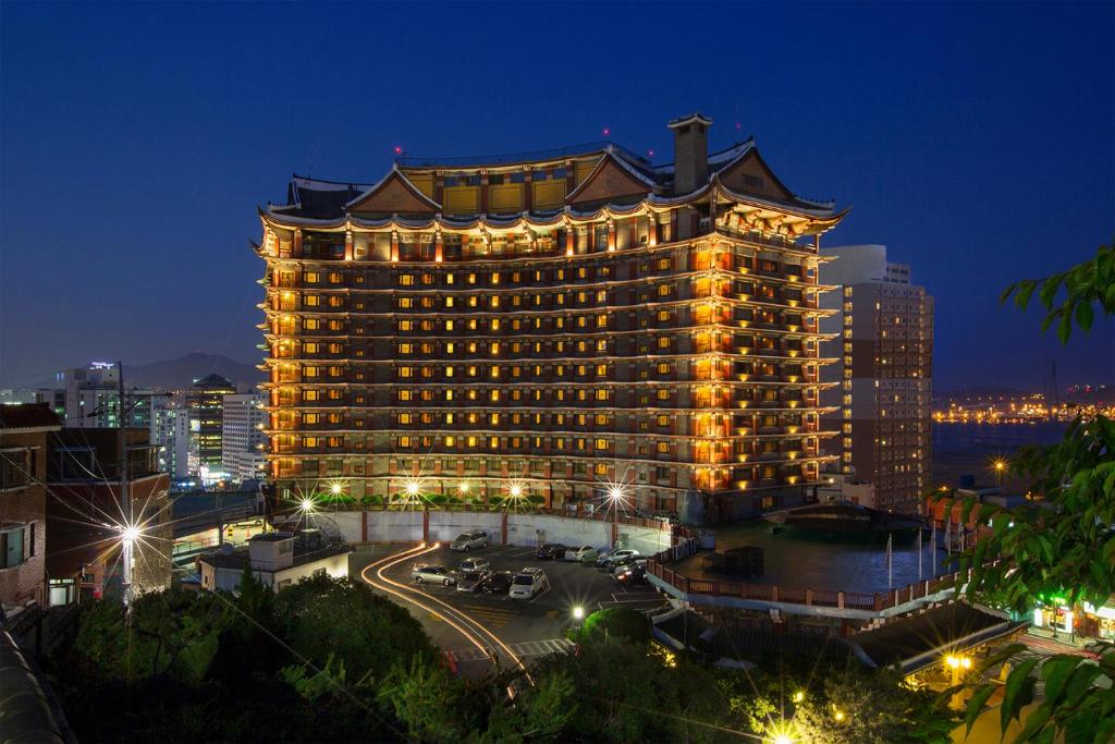 um grande edifício com luzes acesas à noite em Commodore Hotel Busan em Busan