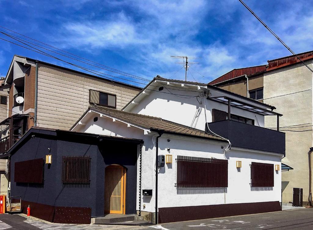 a white and black building on a street at Osaka Guesthouse SAYURI TENGACHAYA Ekimae in Osaka