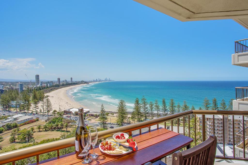 a table with a plate of food and a view of the beach at Gemini Court Holiday Apartments in Gold Coast