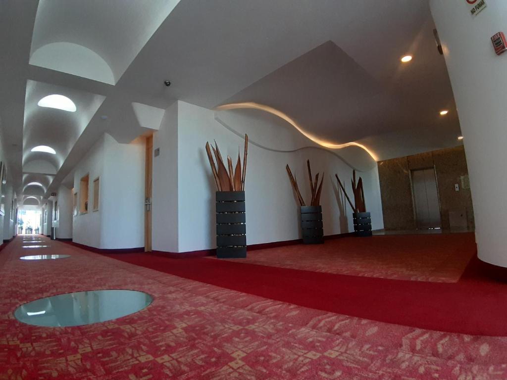 A spacious red-carpeted interior corridor with decorative planters and sculptural ceiling lighting.