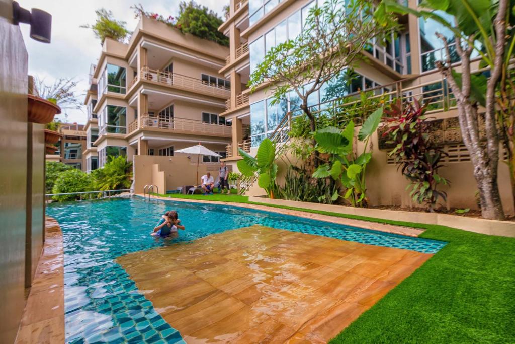 a woman swimming in a swimming pool in front of a building at Karon View Apartments in Karon Beach