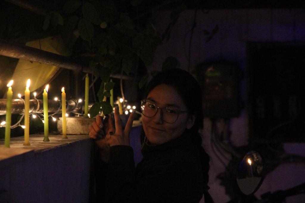 a woman holding up a peace sign in front of lit candles at The Desire Hostel in New Delhi
