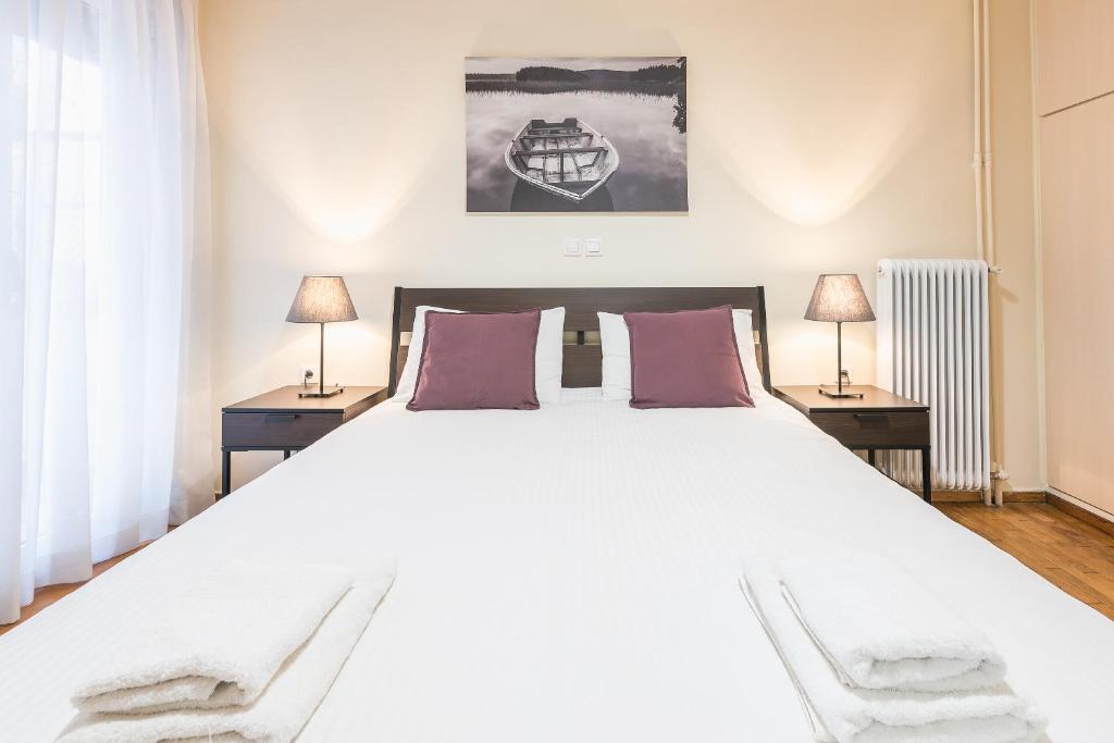 1 dormitorio con 1 cama blanca grande y 2 mesas en Ioannis Cozy Apartment 500 meters from Acropolis museum, en Atenas