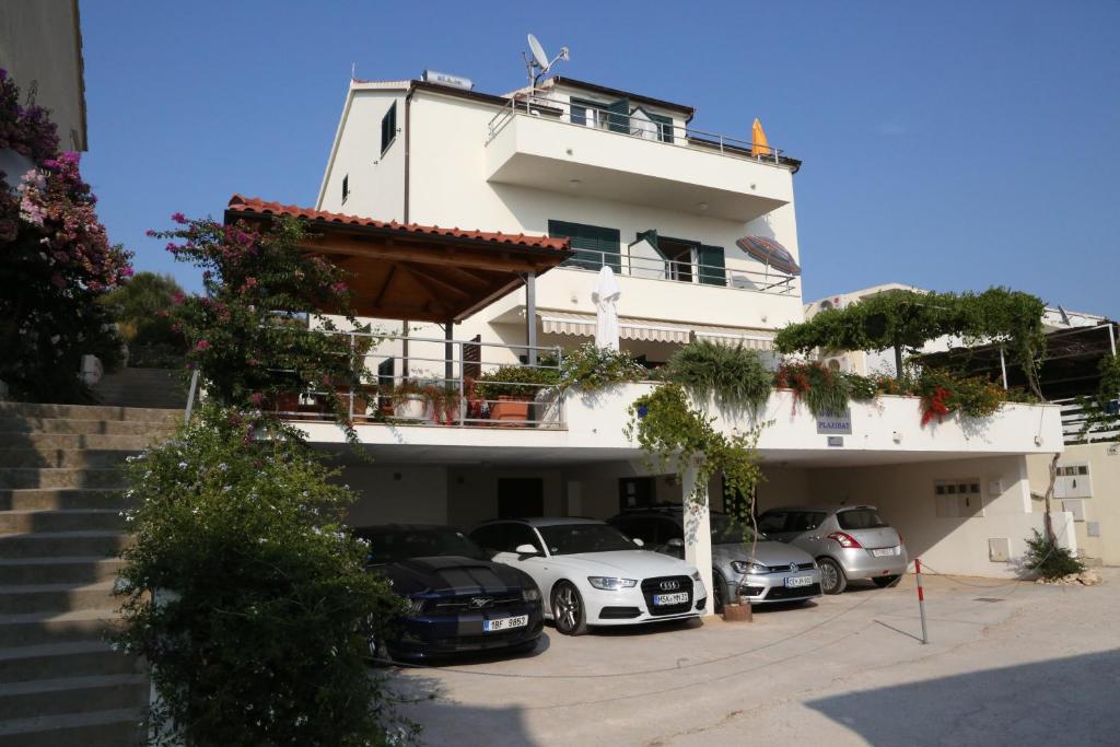 a white building with cars parked in front of it at Apartments Plazibat in Hvar