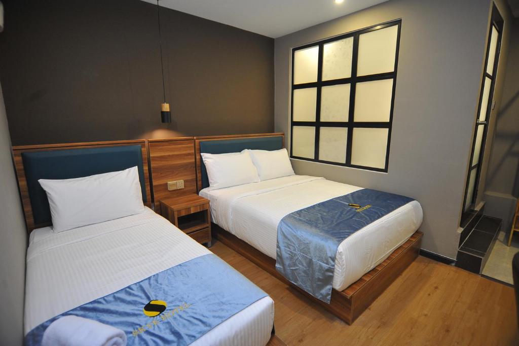 a small room with two beds and a window at Skye Hotel Sunway in Petaling Jaya