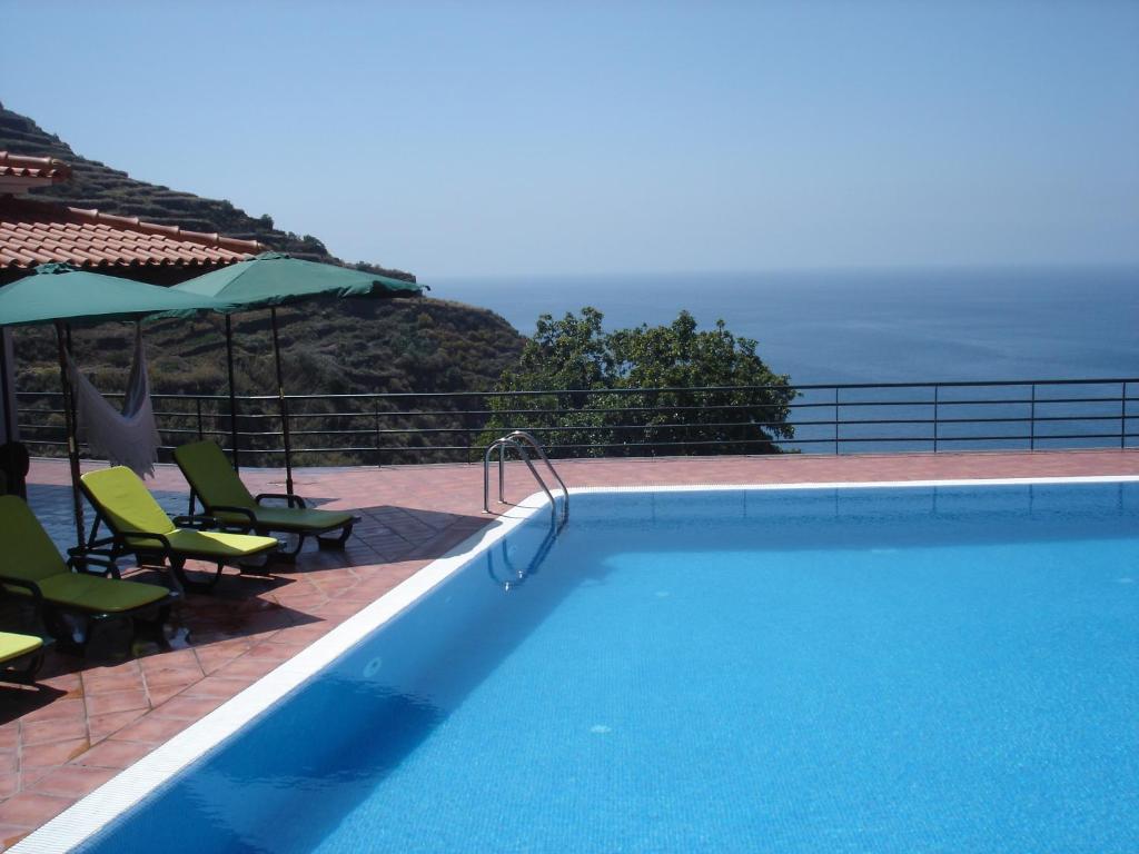 a swimming pool with a view of the ocean at Casa Do Pilrao in Calheta