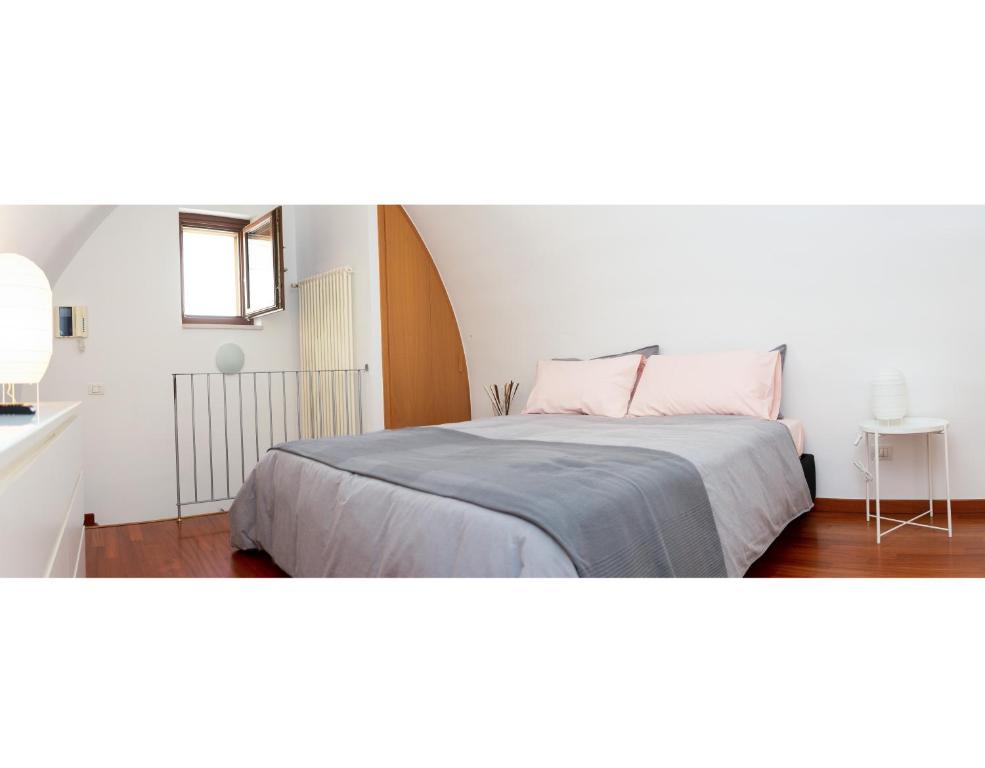 a white bedroom with a bed with a pink pillow at Casa Gnostra in Noci