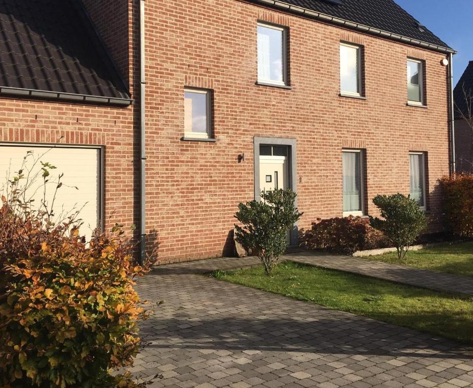 une maison en briques avec deux portes de garage blanches dans l'établissement KIPILI SPIRIT HOUSE., à Nivelles