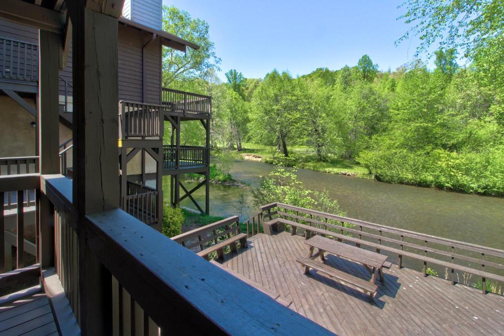a balcony of a house with a bench and a river at Chattahoochee River Edge Condominiums in Helen
