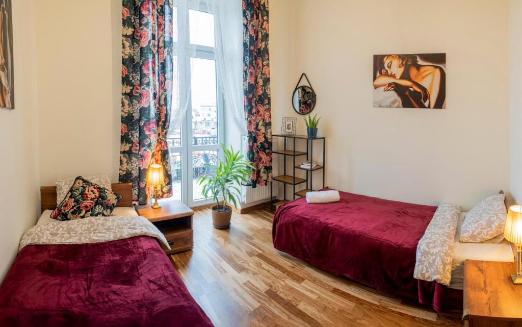 1 dormitorio con cama roja y ventana en Apartamenty Kamienica Rzeszów, en Rzeszów