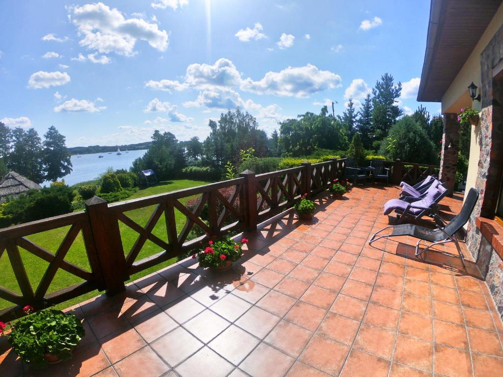 a patio with two chairs and flowers and a fence at Family Lake House in Mikołajki
