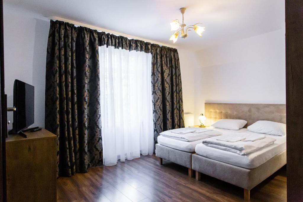 een slaapkamer met 2 bedden en een groot raam bij Gold Rooms in Koszalin