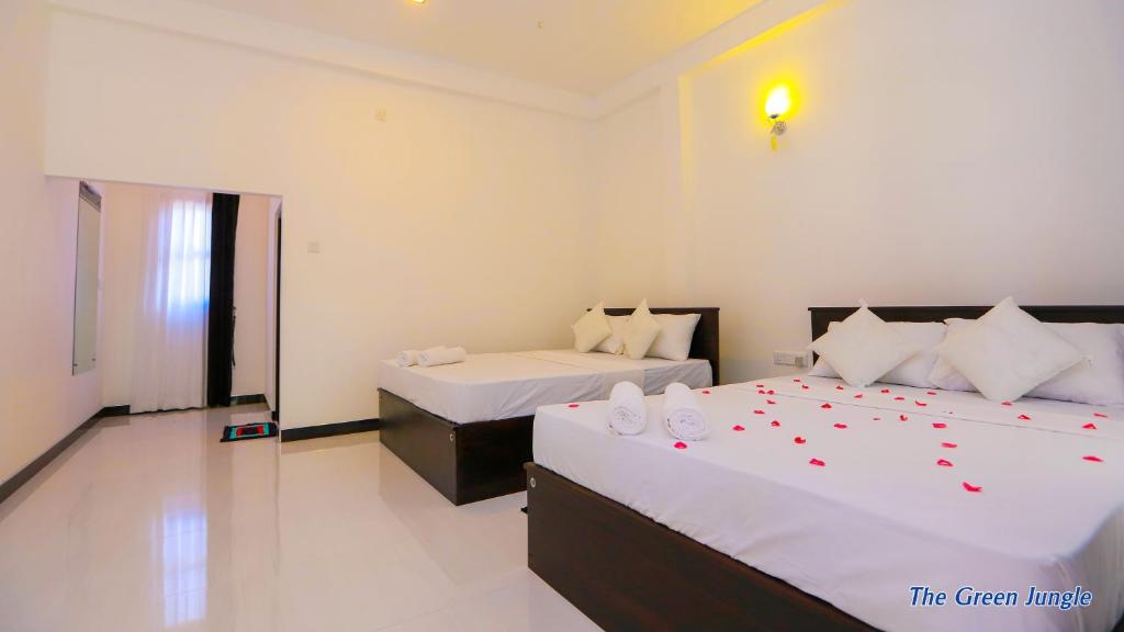 a bedroom with two beds with red rose petals on them at The Green Jungle in Dambulla