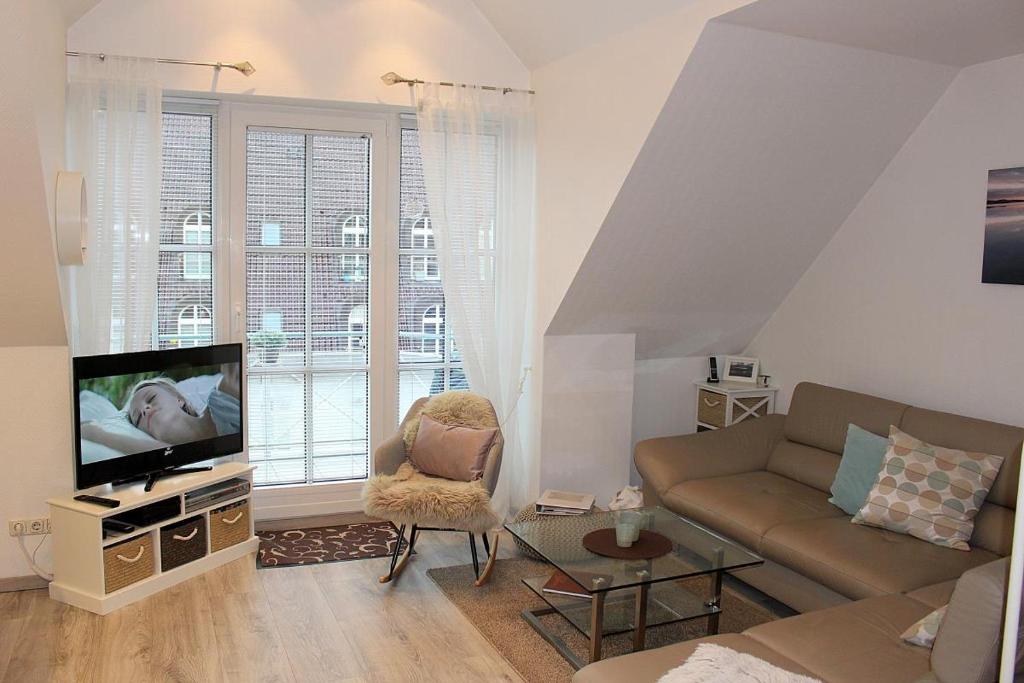- un salon avec un canapé et une télévision dans l'établissement Apartmentvermittlung Mehr als Meer - Objekt 15, à Niendorf