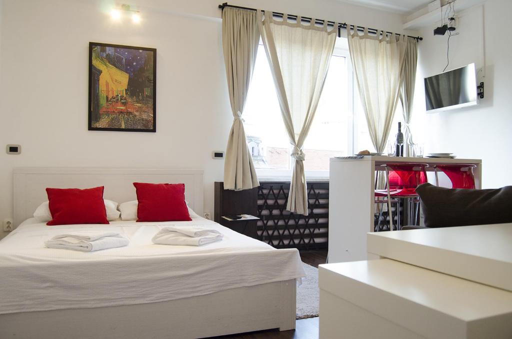 a bedroom with a white bed with red pillows at Studio apartment with a view of Ban Jelačić Square in Zagreb