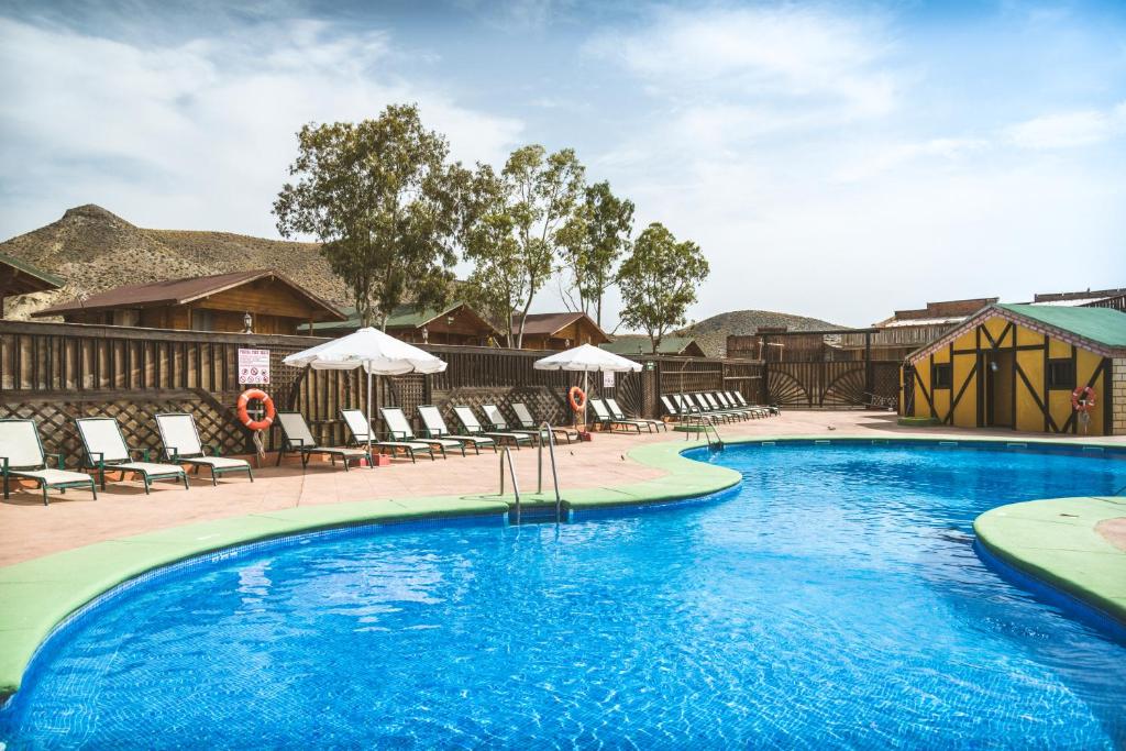 una piscina en un complejo con sillas y sombrillas en Camping Fort Bravo en Tabernas