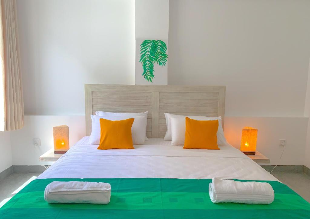 sypialnia z dużym łóżkiem z pomarańczowymi i białymi poduszkami w obiekcie VIBE Hostels w Kolombo
