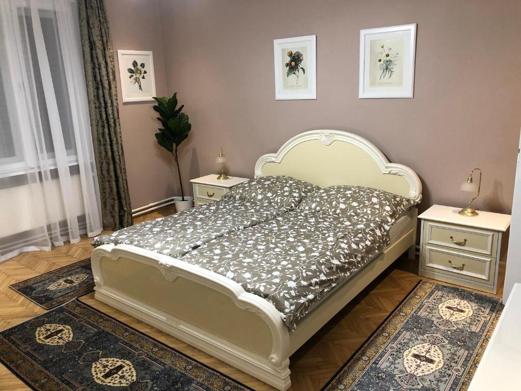 sypialnia z białym łóżkiem i 2 szafkami nocnymi w obiekcie Margaréta Apartman w mieście Pecz