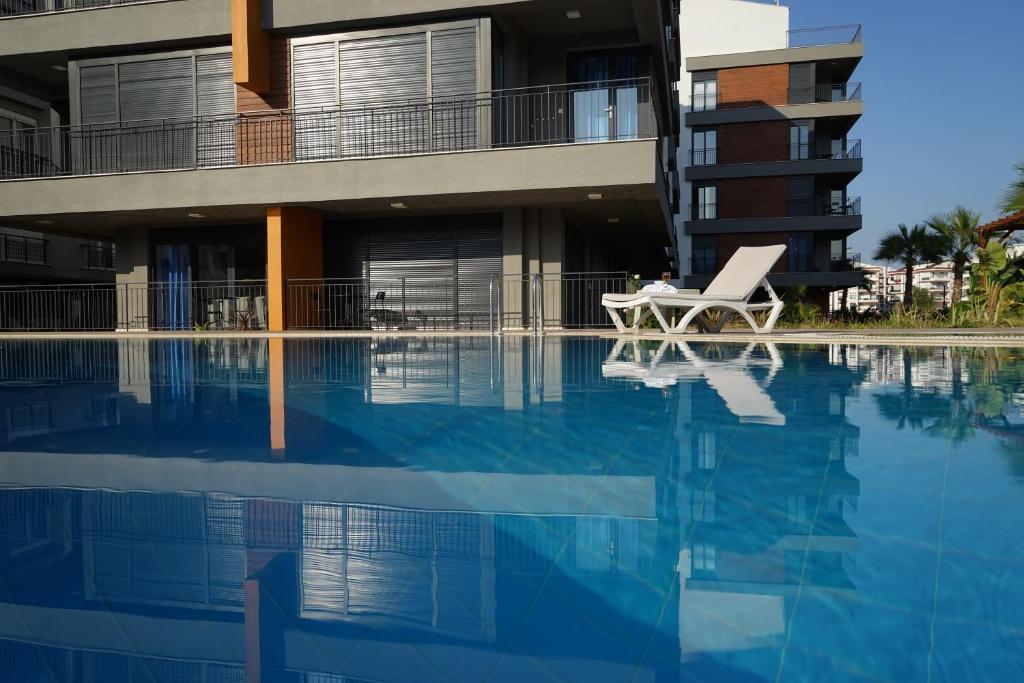 uma piscina com uma cadeira ao lado de um edifício em MENE SUITES em Antalya