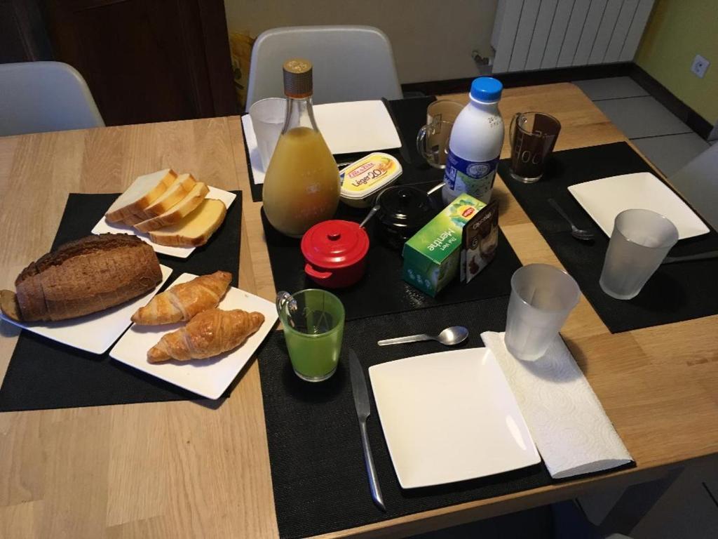 uma mesa com pão, pastelaria e garrafas de leite em chambre double avec salle de bain privative em Cognac