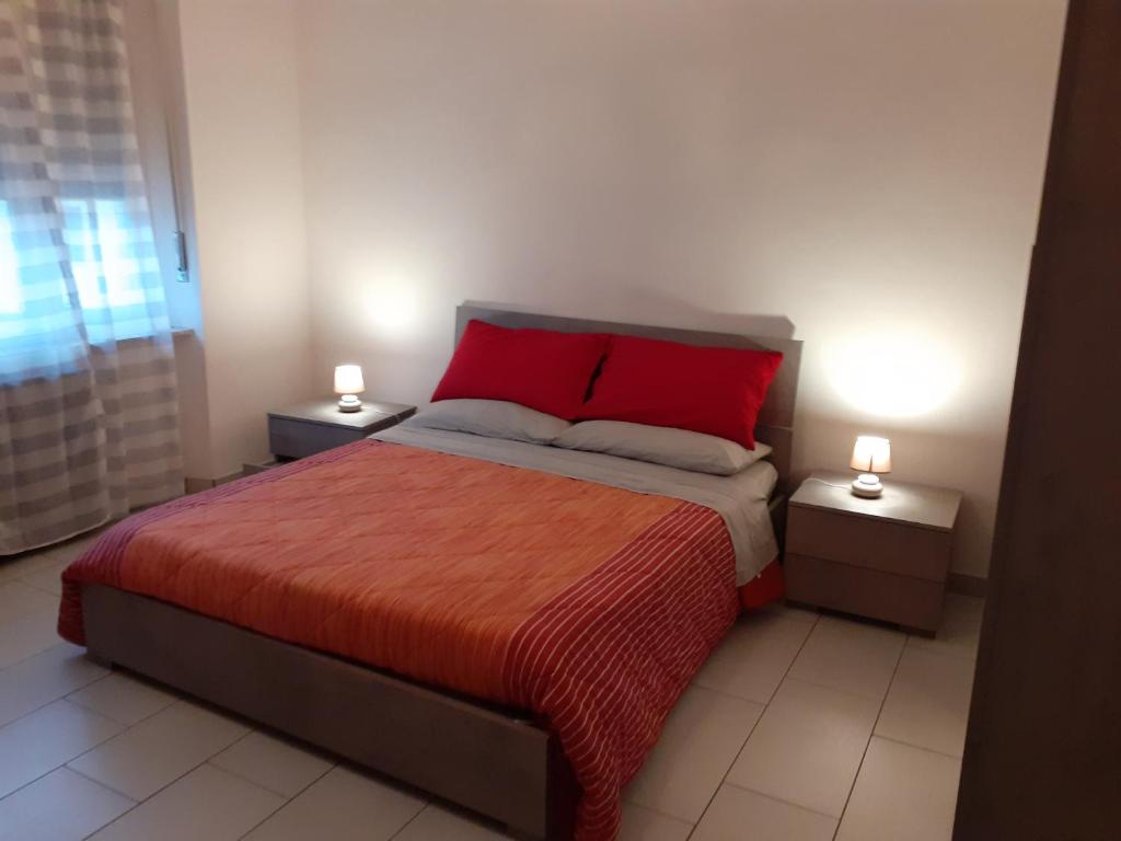 een slaapkamer met een rood bed en 2 nachtkastjes bij la casa di Luca in Asti