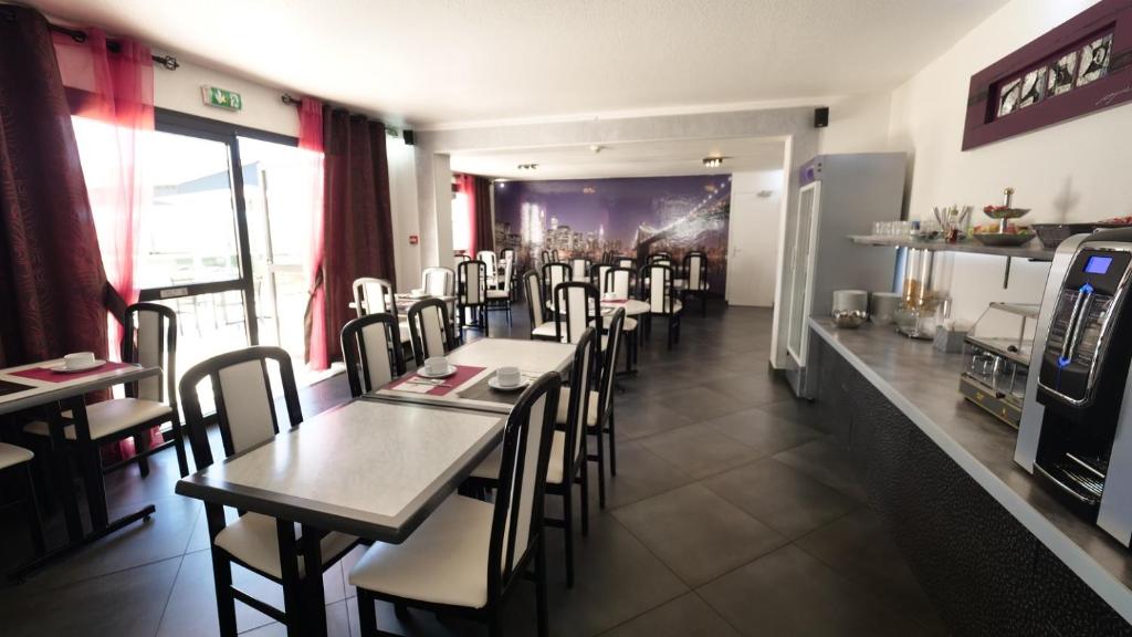 a dining room with tables and chairs in a restaurant at Citotel Hôtel Le Capricorne in Marmande
