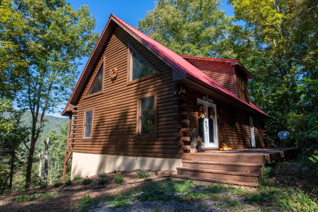 une cabane en rondins dans les bois avec une terrasse couverte dans l'établissement Smokies Overlook Lodge, à Waynesville