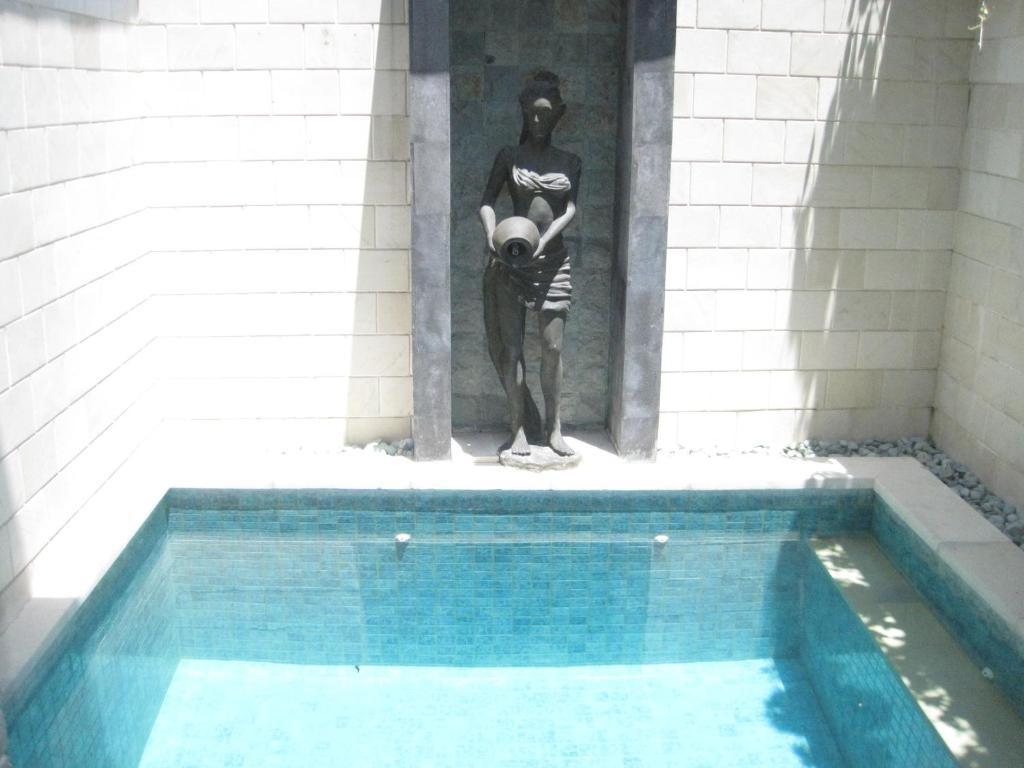 a statue of a man standing next to a swimming pool at Pondok Mirah in Kuta