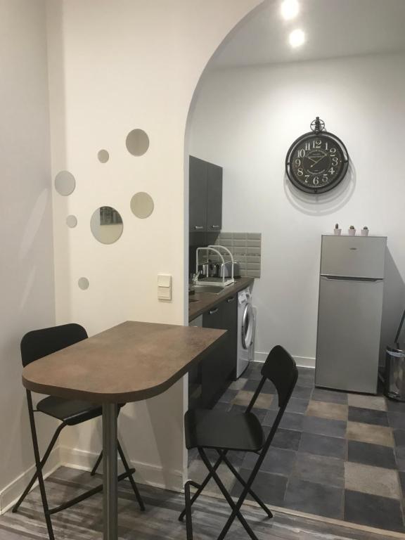une cuisine avec une table, des chaises et un réfrigérateur dans l'établissement charmant studio Pont-Audemer, à Pont-Audemer