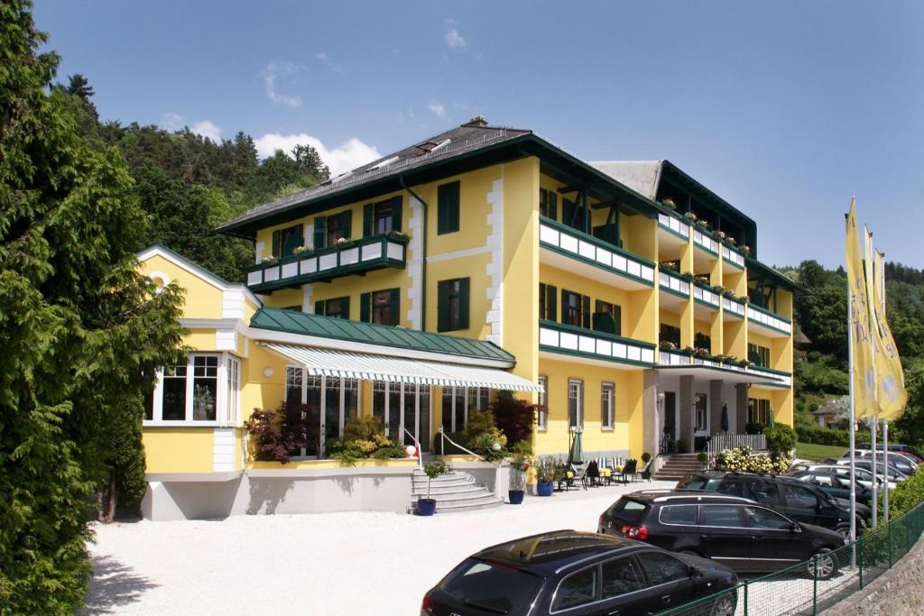 a yellow building with cars parked in front of it at Hotel Kaiser Franz Josef in Millstatt