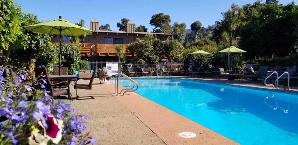 a swimming pool with a table and an umbrella at Carmel Valley Lodge in Carmel Valley