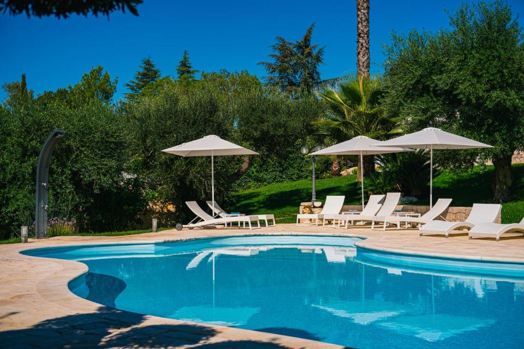 a swimming pool with lounge chairs and umbrellas at Una Perla Nel Verde in Putignano