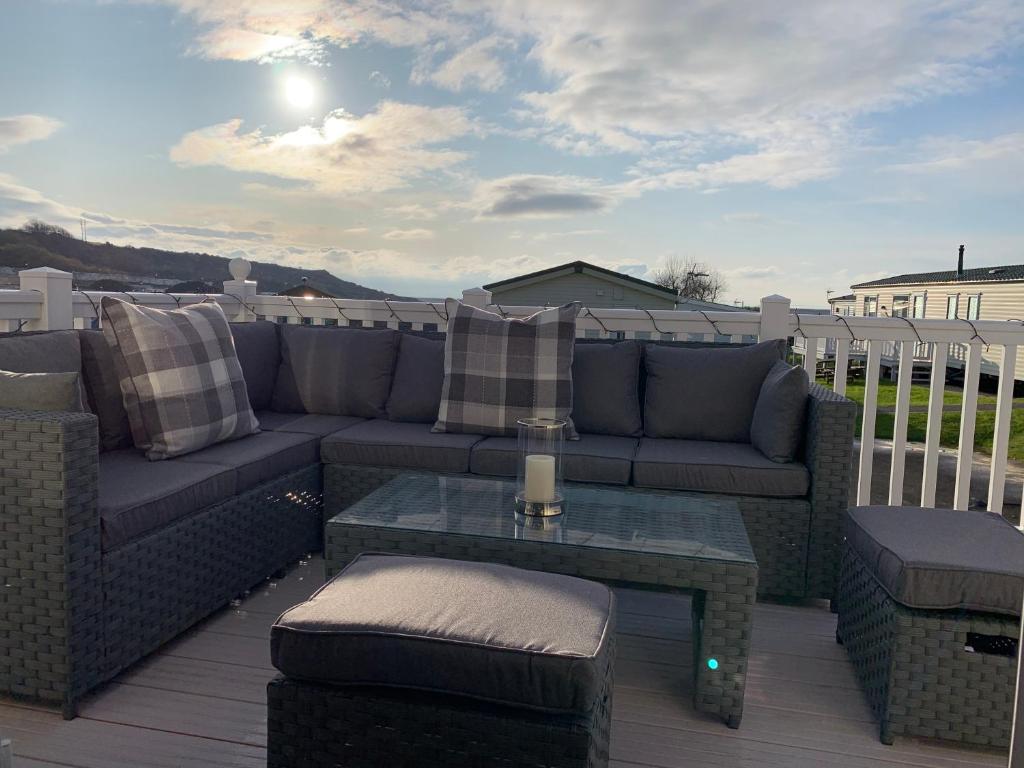 a patio with a couch and a table on a deck at Caravan Littlesea in Weymouth