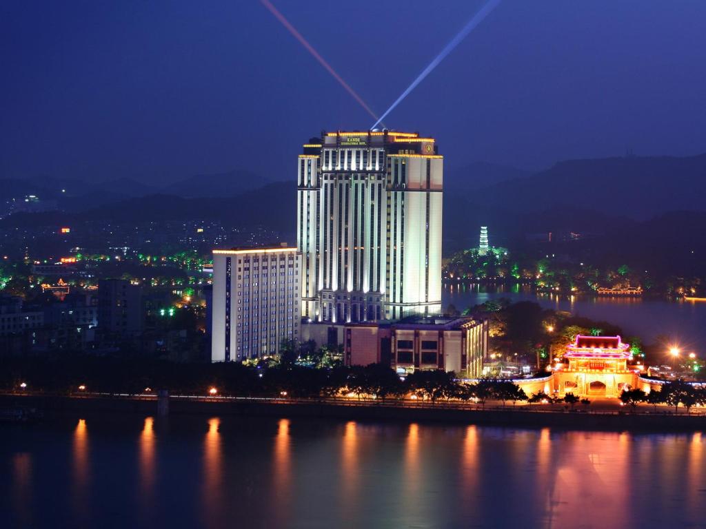 una città illuminata di notte con un grande edificio di Huizhou Kande International Hotel a Huizhou