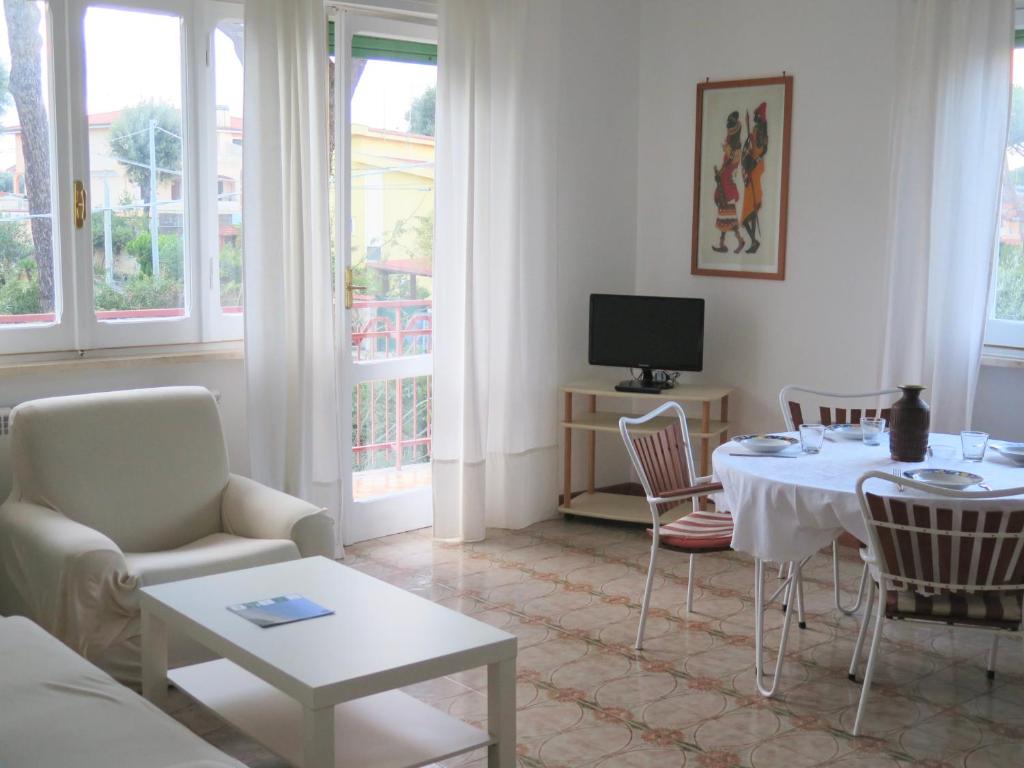 un soggiorno con tavolo, sedie e televisione di The Bright House ad Anzio