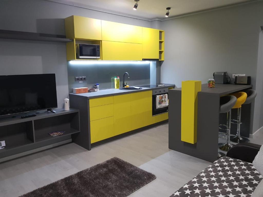 a kitchen with yellow cabinets and a tv at Travel Homzzz Central Apartments - Piata Trandafirilor in Târgu-Mureş