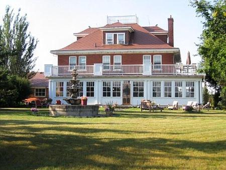 een groot rood bakstenen huis met een grote tuin bij Wakamow Heights Bed and Breakfast in Moose Jaw