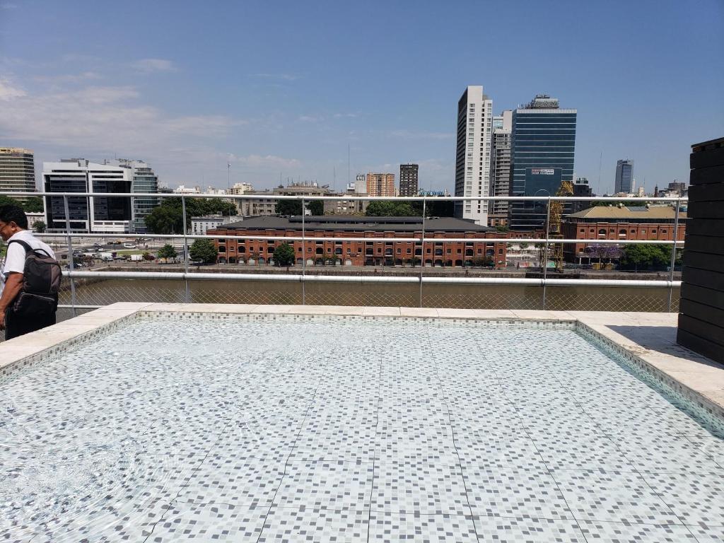 a person standing on top of a roof with a city skyline at Puerto Madero con Amenities in Buenos Aires