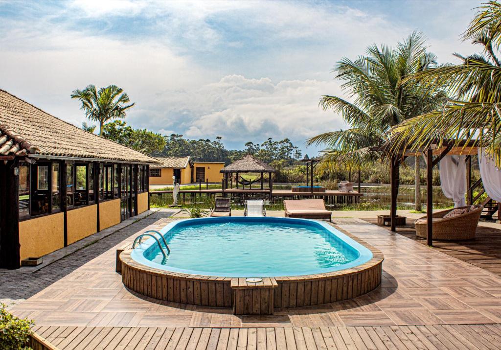 una piscina en un complejo con palmeras en Pousada Xaxá, en Guarda do Embaú